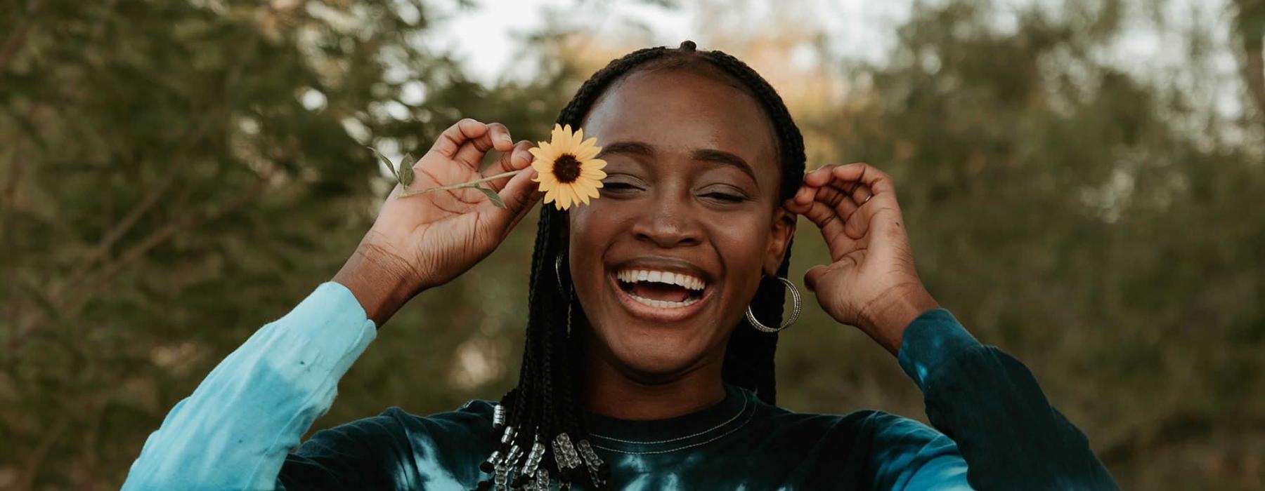woman holds a flower in her hair in a park
